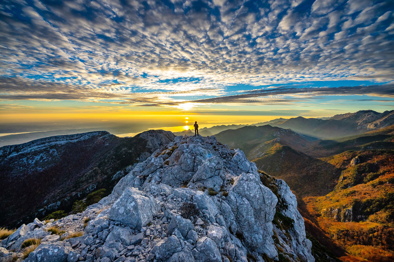 Ein Wanderer auf einem felsigen Berg bei Sonnenuntergang